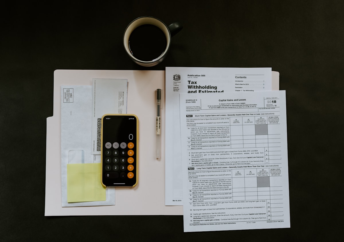 Hands reviewing invoices and a calculator during bookkeeping