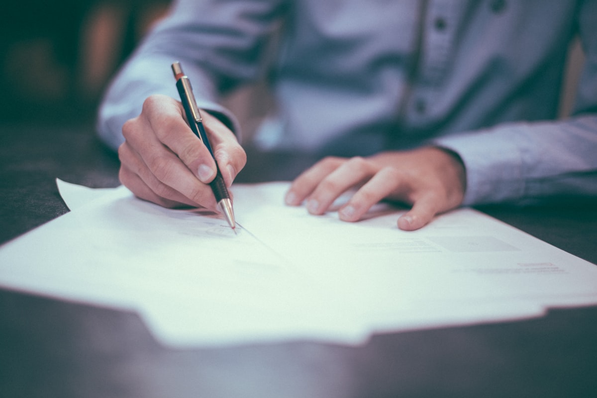 Person signing tax and financial documents at a desk